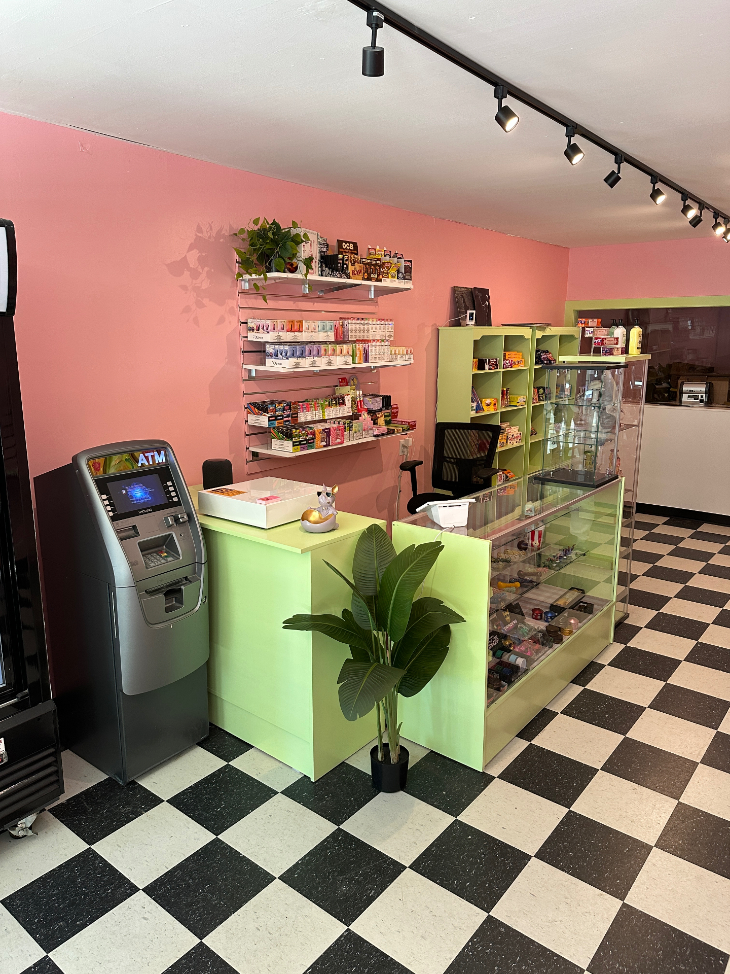 Inside Sugar Mama's — mint green counter, vape shelves, ATM and pink walls